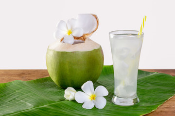 Green coconut fruit cut open to drink juice and eat. Flat lay on green banana leaf and wood background. © Chaded