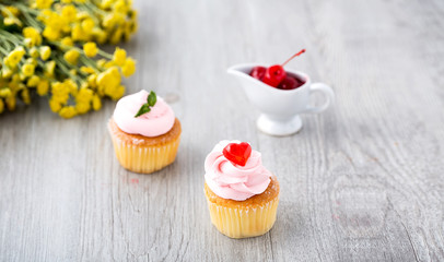 Tasty cupcake on wooden background. Birthday cupcakes on gray wooden background. Cupcakes with heart-shaped jellies. Space for Text.