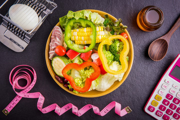 Diet plan, tape measure, calculator for Count calories,  .salad healthy food on black stone background. .Weight loss.
