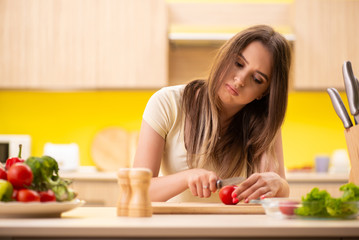 Obraz na płótnie Canvas Young woman preparing salad at home in kitchen