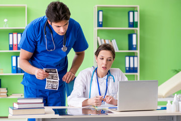 Woman and man gynecologists discussing medical case at the clini
