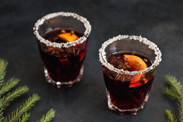 festive cozy christmassy atmosphere. holiday hot drink to warm up. two glasses of spicy mulled wine on black background.