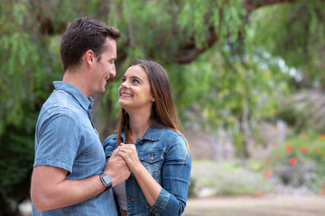Fototapeta premium Beautiful young couple in love holding hands looking at each other with a smile.jpg