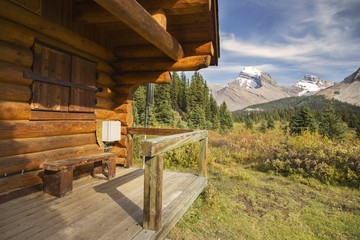 Log Cabin and Distant Snowy Rocky Mountain Tops in Red Deer River Valley, Banff National Park,...