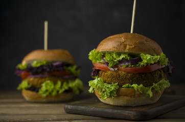 Healthy baked burger with whole grain bun and vegetables on a black board. Vegetarian food concept..