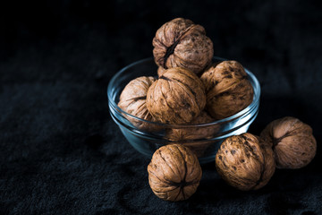 Walnuts in glass bowl on black