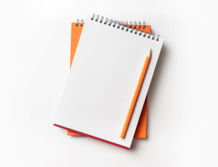 Top view of orange spiral notebook and pencil