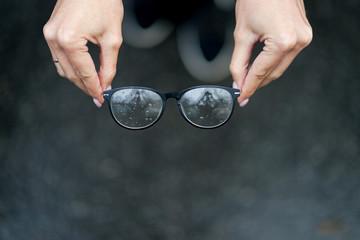 Glasses with rain drops in the girl's hands