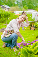 Tired woman planting flowers at back yard