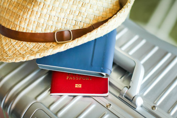 Close up tourist silver suitcase with wicker hat, wallet and passport on it. Ready to travel. Top view