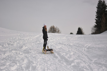 The girl with the sled in the high mountains, a day of fresh snow