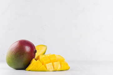 Juicy mango with ripe yellow sliced half on soft light white wood background. Elegant moder kitchen...