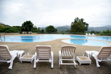 The outdoor swimming pool is in a natural setting with a mountain backdrop.