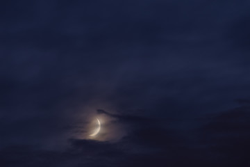 Fototapeta na wymiar Waxing moon in the middle of clouds