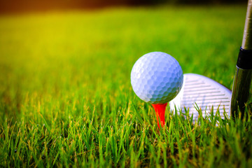 Golf ball and golf clubs on the Course. Golf ball on Orange tee. They are prepare to shot. Photo for health and game. 