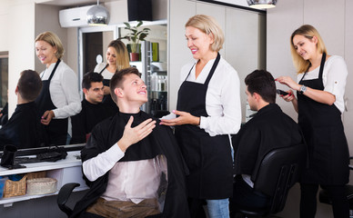 Elderly hairdresser serving teenager