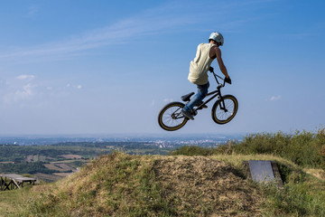 Fototapeta na wymiar Man in helmet on bmx bike jumping and flying on the hill