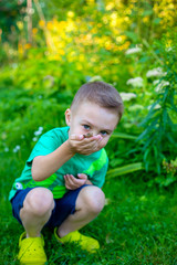 The boy is holding a frog on his hand. Kids discovering