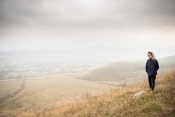 beautiful rural mountain landscape with little girl in jacket with hood overcast