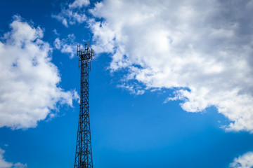 Steel tower with cellular transmitters against a blue sky with clouds