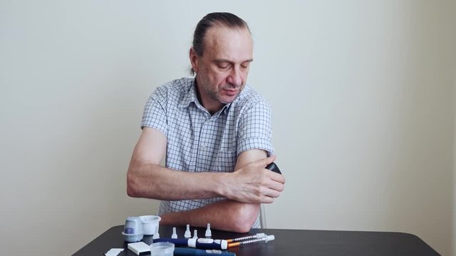 A man brings to the hand the reading device to the sensor for measuring glucose