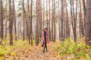 Season, fall and people concept - beautiful young woman walking in autumn park