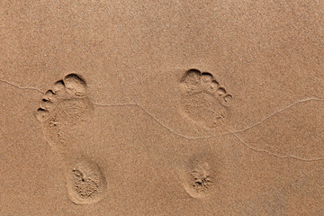 Fototapeta na wymiar Footprints of bare feet in the sand