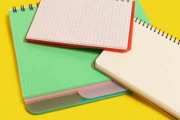 pile of spiral notebooks lying on a yellow background. concept of office stationary