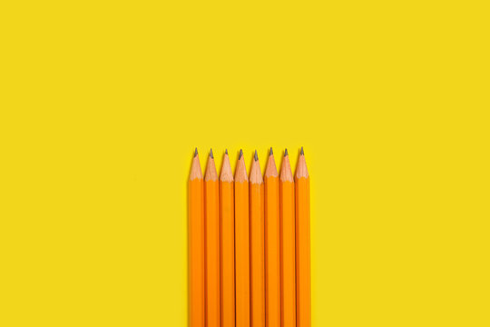 row of new pencils lying on a yellow background. free space for advertising text. concept of office supplies