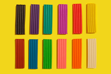 Set of colorful plasticine sticks lying on a yellow background. modeling claying pieces for children play and creativity