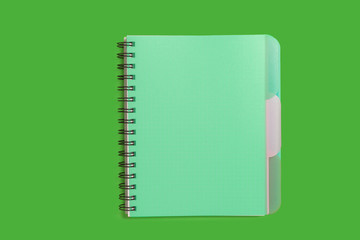 closed spiral notebook lying on a green background. concept of office stationary. free copyspace