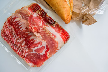 ham and flavor spices, thinly sliced on a white table with bread.
