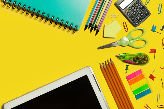 various school and office suplies and gadgets lying on a yellow background. free space for text