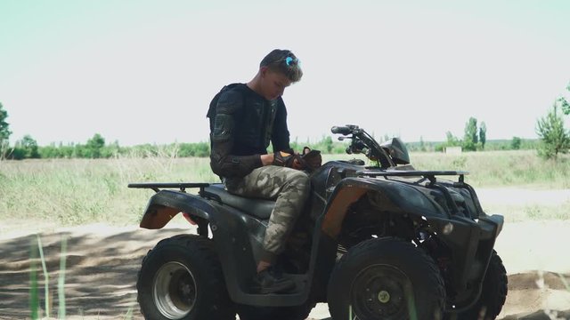 Young man is clicking phone sitting on ATV