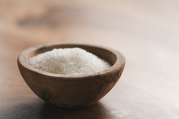 White sugar in wood bowl on table