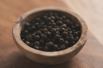 black pepper in wood bowl on table