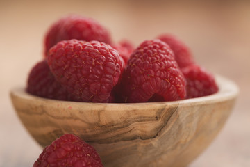 fresh raspberries in wood bowl on table