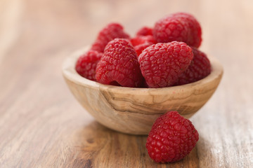 fresh raspberries in wood bowl on table