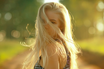 blonde long hair nature summer / happy adult girl with developing in the wind long blonde hair in the summer field