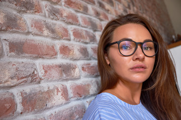 Happy beautiful thinking young woman in glasses looking up. Close up portrait