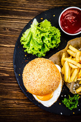 Tasty burger with chips served on black stone plate