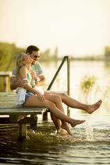 Romantic couple sitting on the wooden pier on the lake