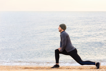 Fototapeta na wymiar man doing stretch exercises on the sea beach