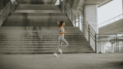 Fototapeta na wymiar Young woman running in the urban environment