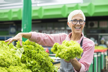 Senior woman sells lettuce on marketplace