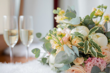 Wedding morning, two glasses of champagne and bride's bouquet of peony and roses.