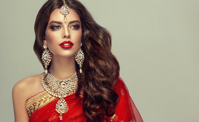 Portrait of beautiful indian girl. Young hindu woman model with kundan jewelry set. Traditional India costume red sari
