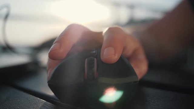 Hands of a business woman with a computer mouse in the sun. Work on the computer in the office or outdoors