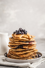 Stack vegan blueberry pancakes with peanut butter and syrup.