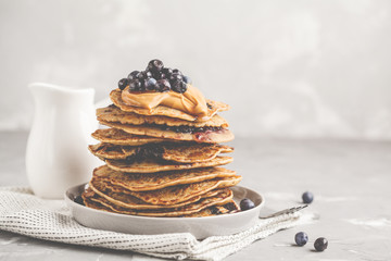Stack vegan blueberry pancakes with peanut butter and syrup.